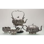 A substantial Burmese white metal four piece tea service, c. 1900, comprising a kettle and burner on