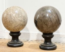 A pair of large marble spheres, one in a grey veined stone, the other mottled light brown, each