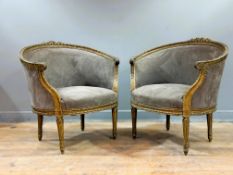A pair of late 19thc French bergeres with giltwood carved foliate backs, with scroll arms, on fluted