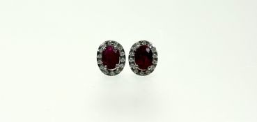 A pair of ruby and diamond cluster earrings set in 18ct white gold, each with an oval-cut ruby