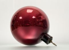A red glass witch's ball, probably early 20th century, with patinated metal flowerhead mount with