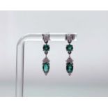 A pair of 9ct white gold pendent earrings each set with an oval emerald (enhanced) of