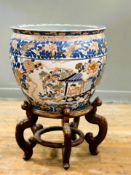 A modern large Japanese porcelain goldfish bowl raised on stained hardwood stand, decorated with