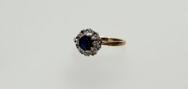 A 18ct gold sapphire diamond cluster ring the round facet cut stone approximately 0.5ct, within a