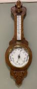 An Edwardian oak barometer, carved floral patera to top over thermometer and barometer, carved