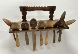 An early 20thc handmade treen carved chipwood wall-mounted spoon rack with a collection of nine