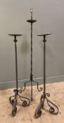 A pair of wrought iron candlesticks, raised on central column and scrolled feet, together with a