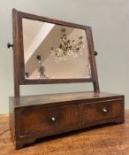 An Edwardian mahogany swing mirror, square plate raised on fluted supports, on a base fitted with