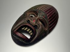 A modern hand-painted and hand-carved tribal style wooden mask, with stylized face and polychrome