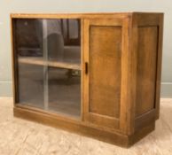 A mid-century oak bookcase, with twin sliding glazed doors enclosing shelf to interior, with panel