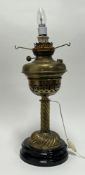 A Victorian brass oil lamp, later converted to a table lamp raised on a stepped base, plug