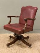 An early 20th century desk chair, oak frame with oxblood leather back and seat, raised on
