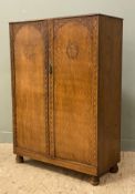 A 1930s carved oak wardrobe, twin panel doors with carved frieze, opening to reveal hanging rail,