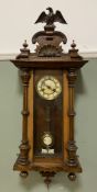 A Victorian walnut Vienna wall clock, eagle finial and turned columns with movement to interior: