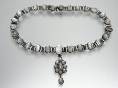 An Edwardian white metal necklace with a panel and alternating oval and circualr moonstone, with a