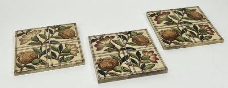 A set of three square ceramic tiles, each decorated with a stylized foliate design with flowering