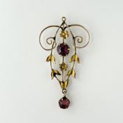 An Edwardian 9ct gold openwork scroll and leaf pendant with a central facet-cut pink stone and
