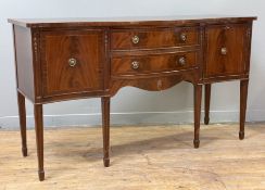 A Regency-style mahogany sideboard, inlaid serpentine top over two central drawers flanked by twin