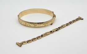 A 9ct gold metal core stiff hinged engraved bangle with clip fastening and safety chain: d. x 6cm