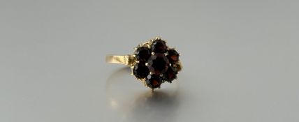 A 9ct gold cluster ring set with seven garnet coloured round stones, the centre stone