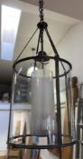 A modern traditional hall lantern, of cylindrical form with bronze finish, opaque glass internal