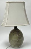 A studio pottery lamp base of bulbous form, decorated with green glaze and hand-painted swirling