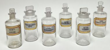 A collection of six 20thc clear glass medicine bottles and stoppers, each with printed Latin