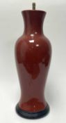 A Mid-Century ceramic table lamp of baluster form, finished in an oxblood style glaze, raised on a