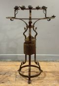 A rusted and weathered wrought iron devotional candle stand, the candle cups on arched supports