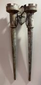 A weathered patinated metal wall-mounted garden double torchere, with crenellated candle cups joined
