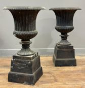 A pair of painted cast-iron Campana garden urns, each on a tapering square section base, 20th