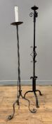 Two wrought-iron floor-standing candle holders, cast with scrolls and each on a tripod base. Heights