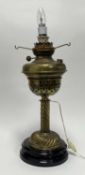 A Victorian brass oil lamp, later converted to a table lamp raised on a stepped base, plug