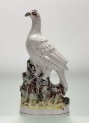 A late 19thc Staffordshire flatback figure of an Exotic Bird figure perched on a mossy bank, chip to