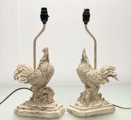 A pair of Rooster table lamps, in a resin distress painted cream, both raised on a plinth base. (h-