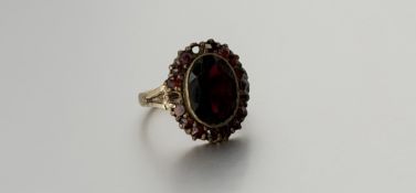 A 9ct gold ring set oval faceted garnet approximately 2ct within a surround of sixteen garent points