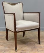 An Edwardian mahogany upholstered armchair, shaped top with bow inlay, raised on square strung