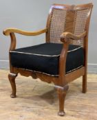 A 1930s walnut bergere armchair, rattan panels to back with scrolled arms, sprung seat cushion
