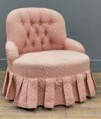 An upholstered child's slipper chair, button-back and arms covered in pink fabric, skirted base