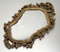 A decorative rococo-style gilt painted foliate and floral carved frame with mirror panel. (