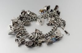 A silver chain link bracelet with heart shaped padlock mounted with thirty two various charms to
