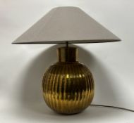 A large hammered brass table lamp of ribbed design, complete with a large brushed linen shade (h.