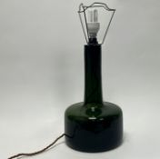 A 20thc dark green glass table lamp in the form of a compressed bottle featuring a rounded bulbous