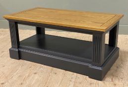 A modern solid oak coffee table, rectangular top over low-level shelf, raised on painted fluted