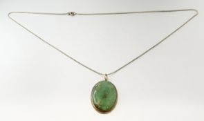 A yellow metal-mounted oval celadon and russet jadite pendant: l. x 4cm w. x 2.5cm on 9ct gold trace