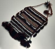 A handwoven kelim saddle bag with bands of polychrome geometric design, accented by beaded strips