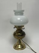 A brass oil lamp style table lamp, complete with a clear elongated shade with an oval frosted shade,