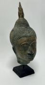 A Thai bronzed head of Buddha, raised on a black painted wooden stand (h. 40cm)