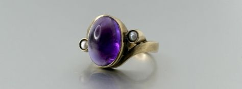 A 9ct gold ring set oval cabochon amethyst approximately 3.5ct within a scroll mount, set a cultured