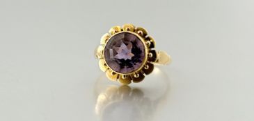 A yellow metal ring set circular facet cut amethyst mounted in beaded petal rub over setting